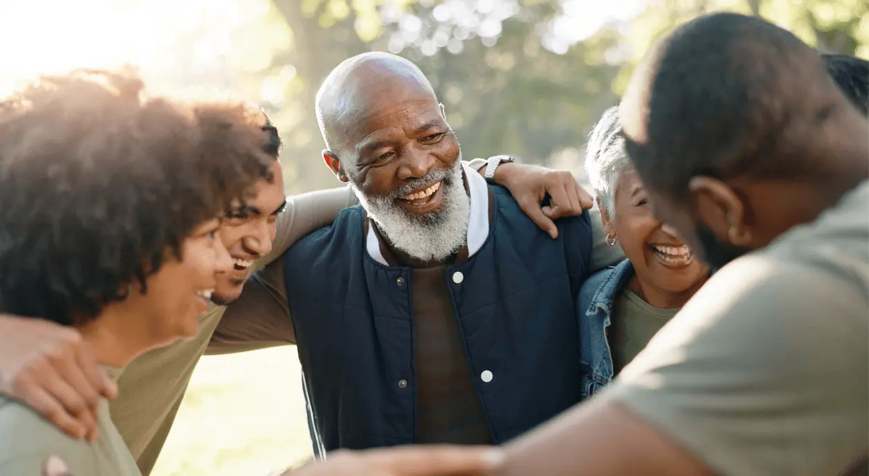 A group of Black Americans in a circle outdoors smiling.