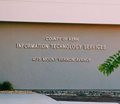 A close-up of a sign that reads COUNTY OF KERN INFORMATION TECHNOLOGY SERVICES 4175 MOUNT VERNON AVENUE.