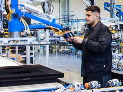 A man holding a device in a factory setting.