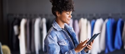 A woman in a denim jacket holding a tablet.