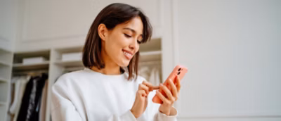 A woman with brown hair smiling while holding a phone.