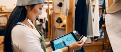 A woman holding a tablet and a credit card.