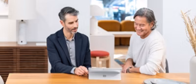 Two people talking to each other while looking at the screen.