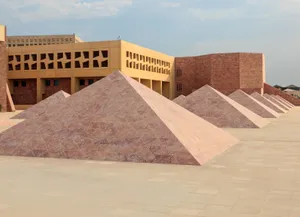 Texas A and M University building in Education City, Doha, Qatar, with a row of pink stone pyramids in the foreground and modern geometric architecture in the background.