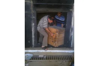 two men lifting wooden box out of a museum