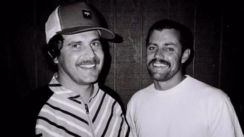 A black and white photo of two men smiling at the camera