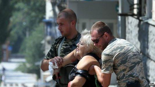 Local men help a wounded woman in Donetsk