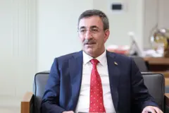 Takım elbiseli kırmızı kravatlı bir erkek oturuyor.