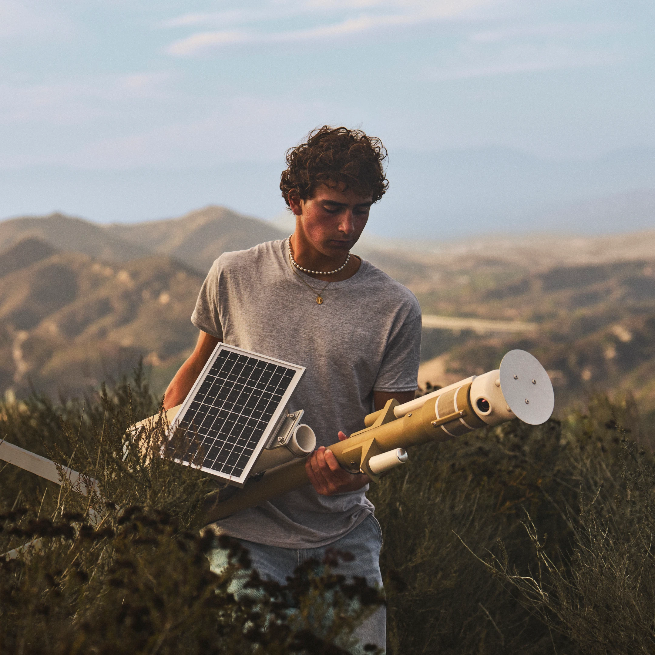 Ryan Honary carries a solar-powered wildfire sensor through dry hills.