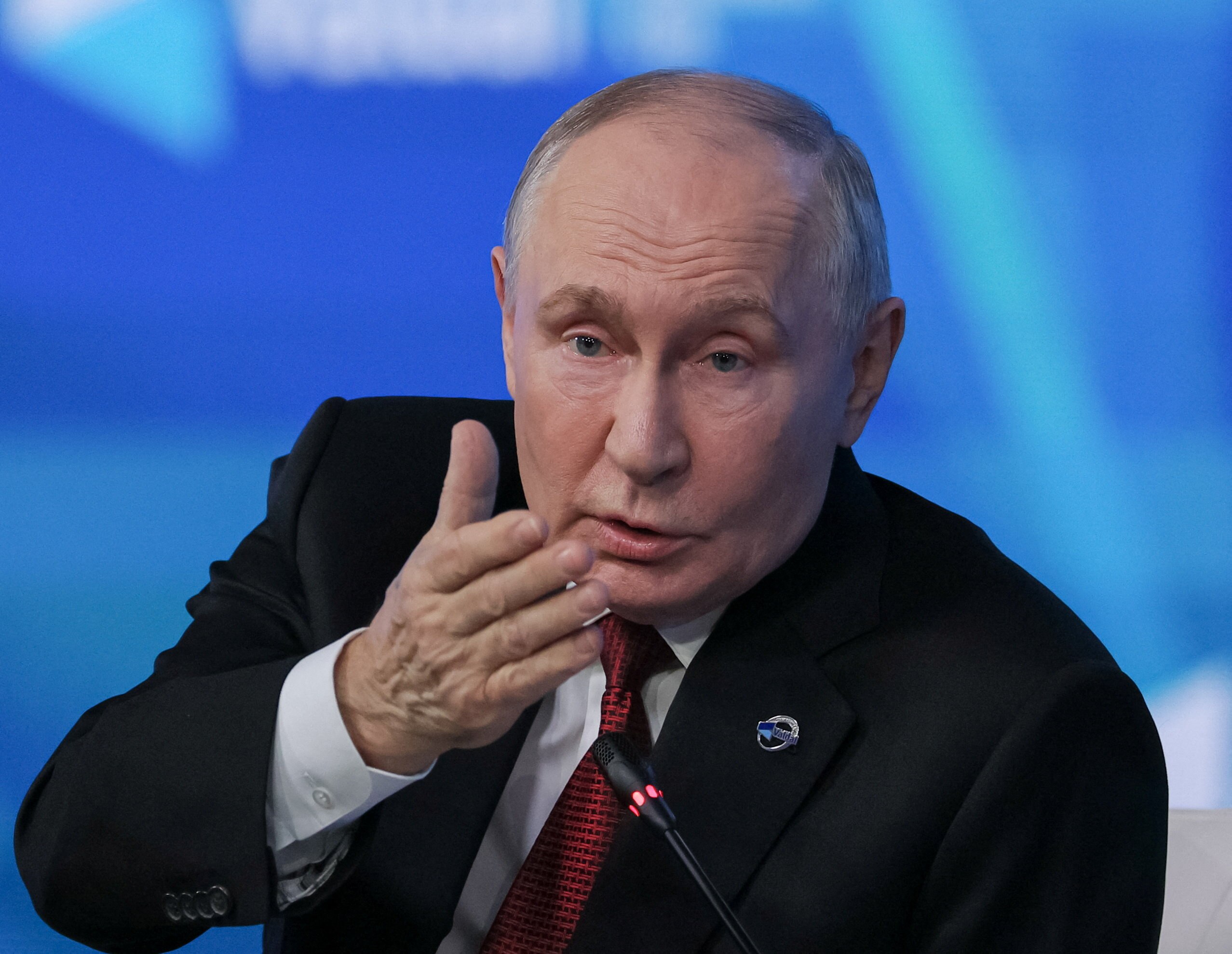 Russian leader Vladimir Putin, bald and in a suit, gesturing seriously