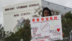 PARKLAND, FL - FEBRUARY 20: Tyra Heman, a senior at Marjory Stoneman Douglas High School, holds a sign that reads, 'Enough No Guns,' in front of the school where 17 people that were killed on February 14, on February 19, 2018 in Parkland, Florida. Police arrested 19-year-old former student Nikolas Cruz for killing 17 people at the high school. (Photo by Joe Raedle/Getty Images)