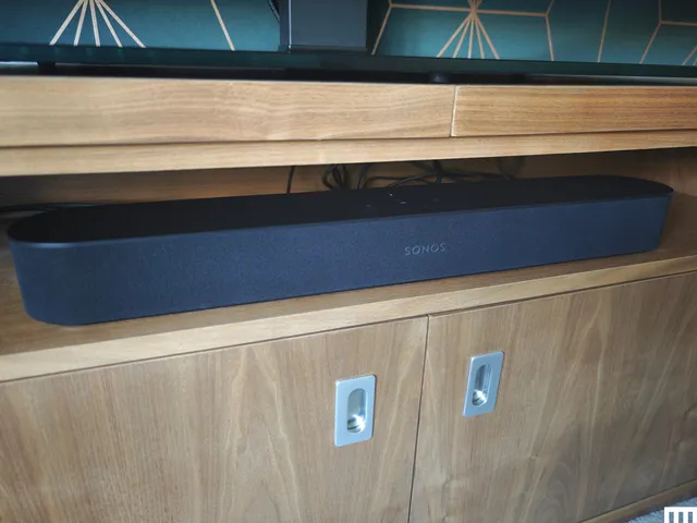 Front view of Sonos Beam Gem 2, a long grey speaker on the shelf of a light brown media console