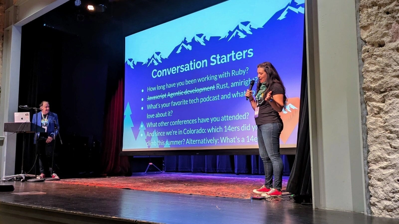 Rocky Mountain Ruby organizers welcoming everyone on the eTown Hall stage, with a Conversation Starters slide