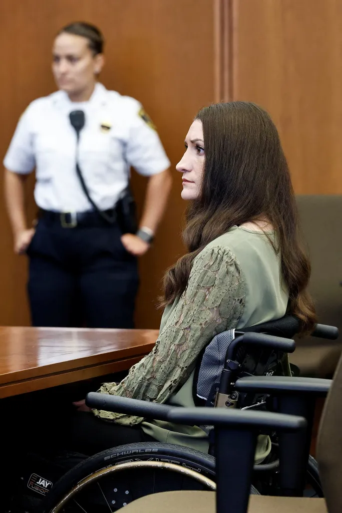 Lindsay Clancy sitting in a wheelchair at Plymouth Superior Court, with an officer standing behind her.