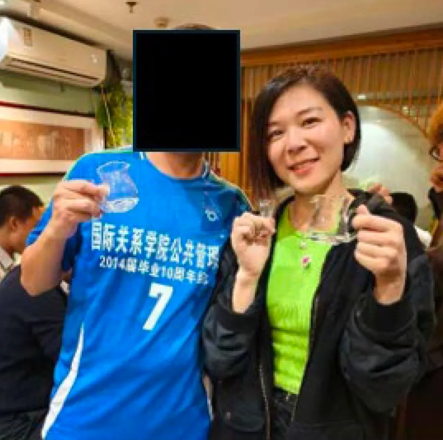 Wanying Zhang, also known as "Heather," standing next to a person in a blue jersey with their face redacted, both holding small glass objects.