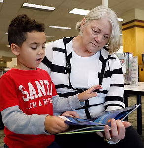 A woman and small boy read a book together