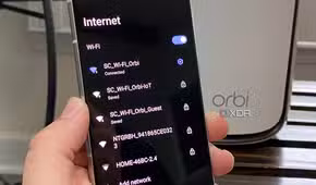 Netgear router with IoT, Guest, and standard Wi-Fi shown on an Android phone