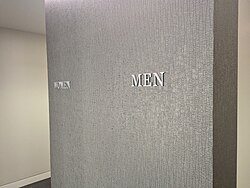 A gray wall with the text "women" and "men" on each side, designating restrooms by gender
