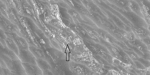 Close view of honeycomb terrain, as seen by HiRISE under HiWish program This enlargement shows material breaking up into blocks.  Arrow indicates a cube-shaped block.