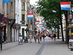 A busy shopping street decorated with Luxembourgish flags on either side