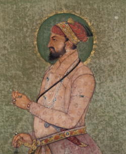 A color portrait, from the waist up, of a bearded man wearing a crown and royal dress