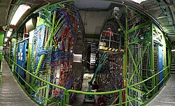Interior do detector CMS, com grandes estruturas circulares, cabos e equipamentos.
