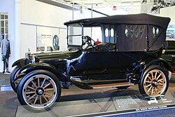 Voiture du début du XXe siècle avec un toit décapotable et un pare-brise vertical.