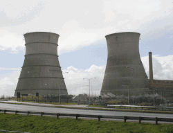 Dust and debris rise as large concrete cooling towers collapse during a controlled demolition