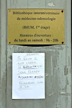 Plaque de la Bibliothèque interuniversitaire de médecine-ondontologie. En dessous affichette manuscrite annonçant la fermeture de la bibliothèque à cause de la chaleur.
