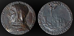Image face et pile d'une médaille couleur bronze. À gauche côté face, un visage de profil tourné vers la gauche avec un nez aquilin et encapuché ; à droite, côté pile, un paysage avec un panorama de ville dont une tour et un haut palais, au-dessus une main pointe une épée vers la ville. Les bords de la médaille comportent une écriture circulaire