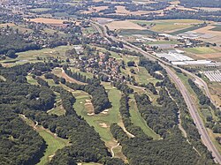 Aerial photograph showing fairways, greens, bunkers, and surrounding landscape at a French golf course near the A40 motorway.