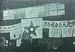 Grainy photo of a meeting with flags and banners