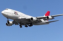 A Boeing 747-400 aircraft in mid-air, with blue sky in the background