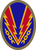 Oval shaped shoulder patch with a deep blue background. Lightning bolts break a yellow chain, representing the liberation of Nazi-occupied Europe.
