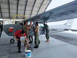 Colour photo of people working on an aircraft on the ground