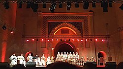 Concert stage with a band performing and the gate of Bab Dekkakin in the background