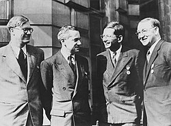 Four men in suits, each sporting a medal on the left breast