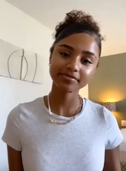 Photo de la chanteuse Tyla en 2022 plan américain. Elle porte un tshirt blanc simple.