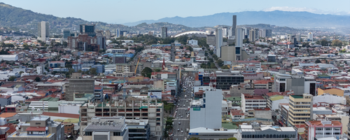 Panorama bandar San José dengan bangunan-bangunan tinggi dan gunung di latar belakang