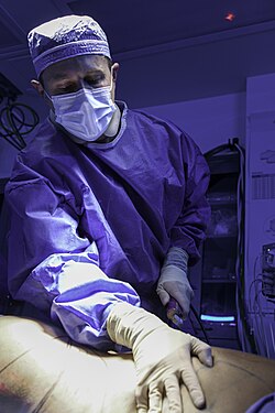 Surgeon performing power-assisted liposuction with a motorized cannula in an operating room.