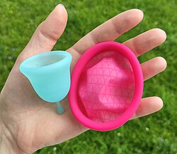 A menstrual disc and menstrual cup are held next to each other. The disc is larger in diameter and flatter. It has a similarly thick rim and thinner material in the basin.
