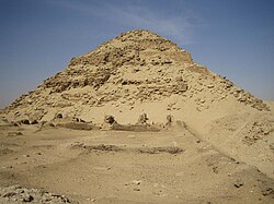 Large but ruined pyramid made of limestone and bricks in the desert.