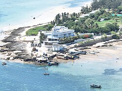 Aerial photograph of a beachfront hotel in Vilankulo, surrounded by palm trees, boats and shallow turquoise water.