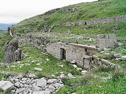 Stone remains of a building, lying on a grassy hill