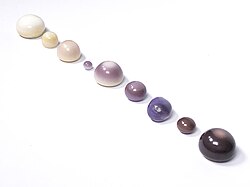 A collection of natural quahog pearls ranging from white to dark purple.