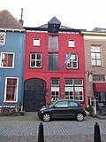 Pakhuis achter gepleisterde lijstgevel met hijsbalk