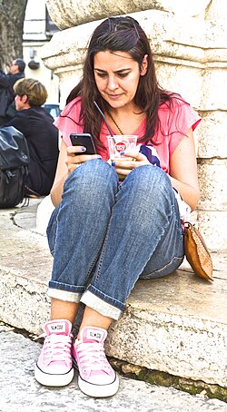 Mulher consulta textos na tela de um telefone celular.