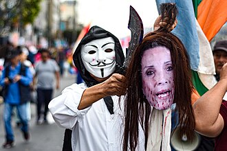 Manifestante, vestido con máscara de anonymous, sostiene maniquí con la cabeza de Dina Boluarte. Protestas contra Dina Boluarte.