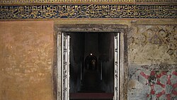 rectangular doorway with a strip of calligraphed text across the wall above