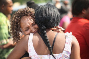 CHICAGO, IL - JULY 20: Friends comfort each other during a memorial service for Shamiya Adams on July 20, 2014 in Chicago, Illinois. Jalante, along with family members, prepare to release ballons during a prayer vigil. Adams, 11, was killed while spending the night at a friend's home when a stray bullet flew through an open window and an interior wall and struck her in the head on July 18th. The memorial service was held outside of the home in which Adams was killed. (Photo by Scott Olson/Getty Images)